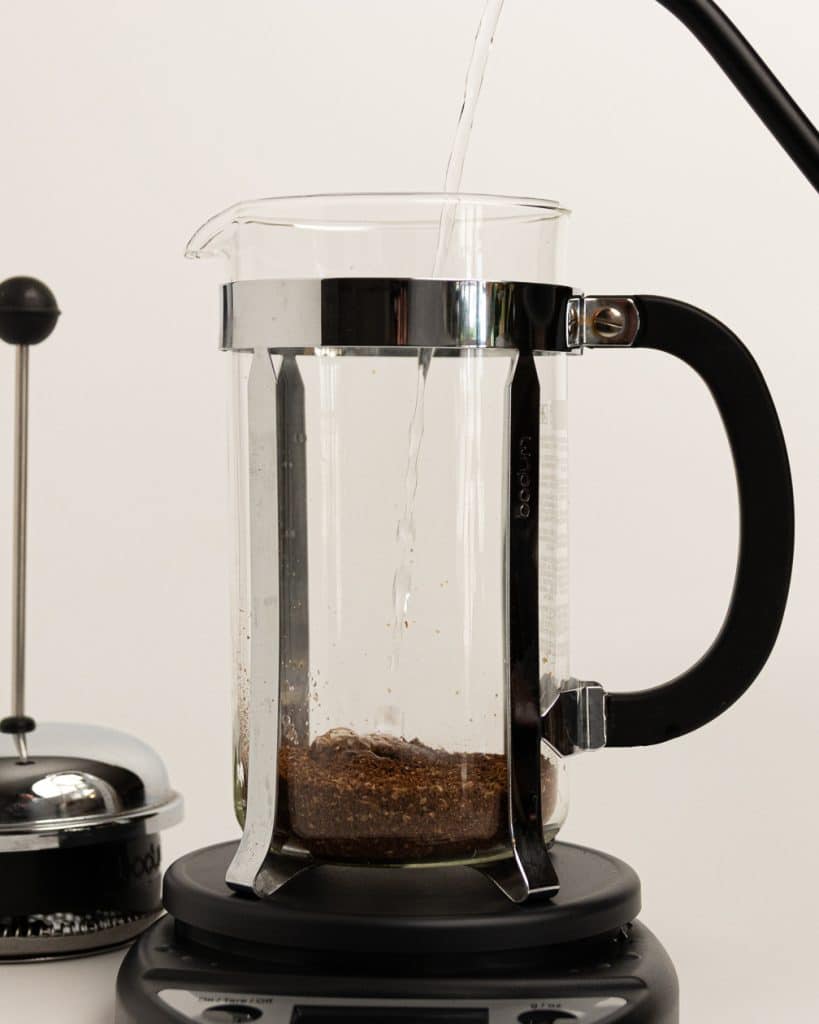 hot water being poured over grounds in a French press base